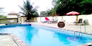 uma grande piscina com cadeiras e um guarda-sol em Room in Lodge - Tiffany Hotels and Towers em Imogwu-Agwa