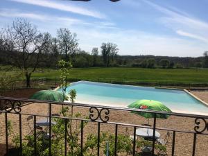 einen Pool mit zwei Sonnenschirmen auf einem Balkon in der Unterkunft Maison d'hôtes " Ecuries de St maurice" in Lacapelle-Marival