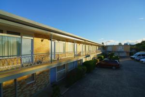 an apartment building with a parking lot and a car at Olympia Motel in Queanbeyan