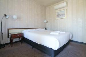 a hotel room with a large bed and a table at Olympia Motel in Queanbeyan