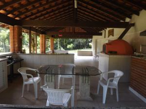 un patio con mesa de cristal y sillas blancas en Sitio do Tonetti, en Mairiporã