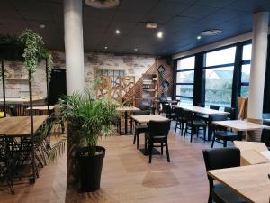 a restaurant with tables and chairs and large windows at le Ricordeau in Domagné