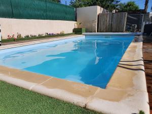 a swimming pool with blue water in a yard at La Grange des Griottiers in Saint-Priest