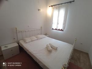 sypialnia z łóżkiem z białą pościelą i oknem w obiekcie elaiolithos w mieście Kóstos
