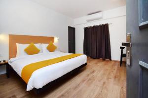 a bedroom with a large bed with yellow and white pillows at FabHotel The Sky I in Kolkata