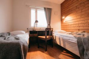 a bedroom with two beds and a desk and a window at Lapland Hotels Kilpis in Kilpisjärvi