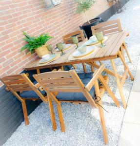 een houten tafel en stoelen naast een bakstenen muur bij Snurk Texel in Den Burg