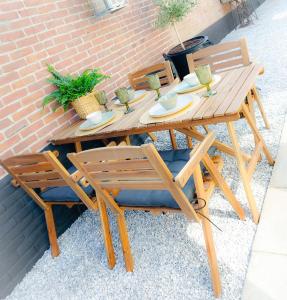 a wooden table and chairs sitting next to a brick wall at Snurk Texel in Den Burg