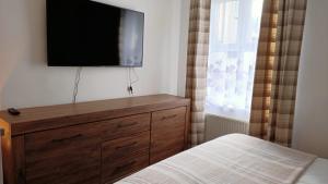 um quarto com uma cómoda e uma televisão de ecrã plano na parede em The Old Surgery em Blaenau-Ffestiniog