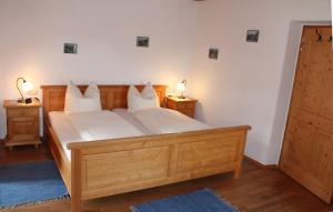 Un dormitorio con una gran cama de madera con almohadas blancas. en Grafn-Hof en Schleching