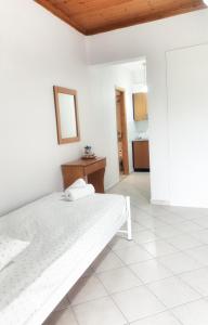 a white bedroom with a bed and a mirror at Orange Apartments in Vasiliki