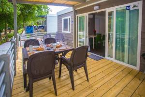 a patio with a table and chairs on a deck at CHERRY Premium JADE Mobile homes Zelena Laguna in Poreč