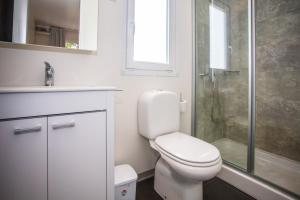 a white bathroom with a toilet and a shower at CHERRY Premium JADE Mobile homes Zelena Laguna in Poreč +15 photos