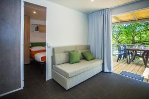 un soggiorno con divano, letto e patio di CHERRY Premium JADE Mobile homes Zelena Laguna a Poreč (Parenzo)