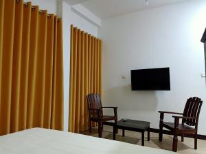 a room with yellow curtains and two chairs and a tv at Greenfield Bedz in Hatton
