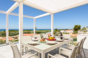 a dining room with a table and chairs and a view of the ocean at Villa Dolce Vita in Son Bou
