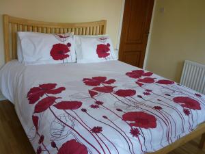 Gayton Bed & Breakfast في هامبتون إن آردِن: سرير مع زهور حمراء على لحاف أبيض