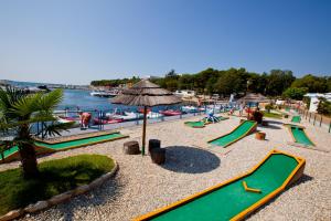 a playground with slides and an umbrella next to the water at CHERRY Premium JADE Mobile homes Zelena Laguna in Poreč