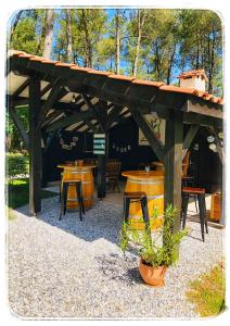 a wooden pergola with tables and chairs in a park at Au Clair Des Landes in Castets