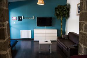 a living room with a couch and a tv on a blue wall at Hôtel Les Pieux En Cotentin in Les Pieux