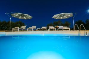 a swimming pool with chairs and umbrellas at Villa Parisa in Božava