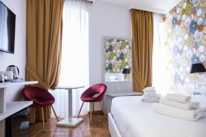 a hotel room with a bed and two red chairs at Hotel Cinquantatre in Rome