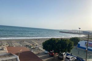 une plage avec des voitures garées sur le sable et l'océan dans l'établissement Maravilloso apartamento en primera linea de playa con vistas al mar en Caleta de Vélez 2 D, à Caleta De Velez