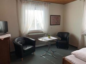 um quarto com duas cadeiras, uma mesa e uma cama em Hotel Garni Siedlerstube em Nürtingen