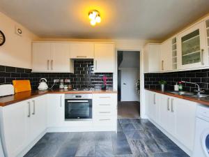 uma cozinha com armários brancos e azulejos pretos em Dean House, 2 BR, Sleeps 5,Kitchen, FREE Parking, Spacious, Garden, Close Motorways em Doncaster