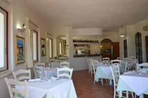 un restaurante con mesas blancas y sillas blancas en Hotel La Palma, en San Teodoro