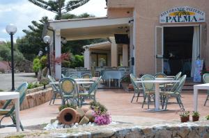a group of chairs and tables on a patio at Hotel La Palma in San Teodoro