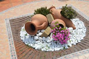 a rock garden with vases and flowers on a sidewalk at Hotel La Palma in San Teodoro
