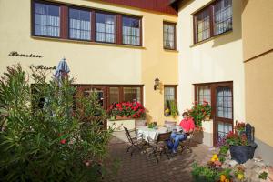 a woman sitting at a table outside of a building at Landpension Risch in Ilmenau