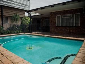 a swimming pool in front of a house at Dunwoodie Travel Lodge in Pretoria