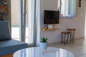 a living room with a couch and a table and a tv at San Tito in Mochlos
