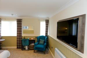 a hotel room with a large tv and a blue chair at Duck Bay Hotel & Restaurant in Balloch