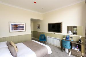 a hotel room with a bed and a desk and a tv at Duck Bay Hotel & Restaurant in Balloch
