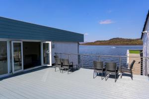 a group of chairs sitting on a deck next to the water at Duck Bay Hotel & Restaurant in Balloch