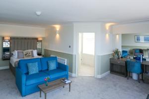 a living room with a blue couch and a bed at Duck Bay Hotel & Restaurant in Balloch