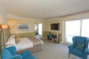 a bedroom with a bed and two blue chairs at Duck Bay Hotel & Restaurant in Balloch