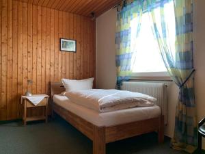 a small bedroom with a bed with a window at Hotel Garni Siedlerstube in Nürtingen
