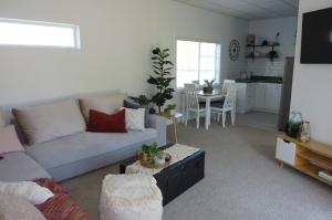 a living room with a couch and a table at Rustling Oaks NZ Boho Pool House in Cambridge