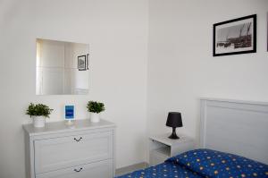 Schlafzimmer mit einem Bett, einer Kommode und einem Spiegel in der Unterkunft Case Vacanze Farchikalà in Lampedusa
