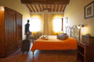 mężczyzna stojący w sypialni z łóżkiem w obiekcie Fattoria Fibbiano w mieście Terricciola