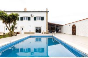 a villa with a swimming pool in front of a house at Quinta do Selão in Cabanas de Torres