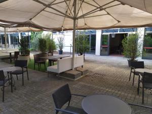 patio ze stołami i krzesłami pod parasolem w obiekcie Ferretti MajesticHouse w mieście Castenedolo