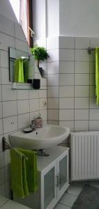 ein Badezimmer mit einem weißen Waschbecken und grünen Handtüchern in der Unterkunft *To hus* Wohnung am Rande von Jever in Jever