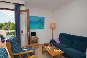 un soggiorno con divano blu e sedie di Apartamento Playa Dor 14 a Cala d´Or