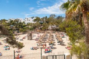 Grupa ludzi siedząca na plaży z parasolami w obiekcie Apartamento Playa Dor 14 w mieście Cala d´Or