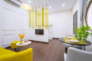 uma sala de estar com uma mesa e cadeiras amarelas em Sun City Hotel Da Nang em Da Nang